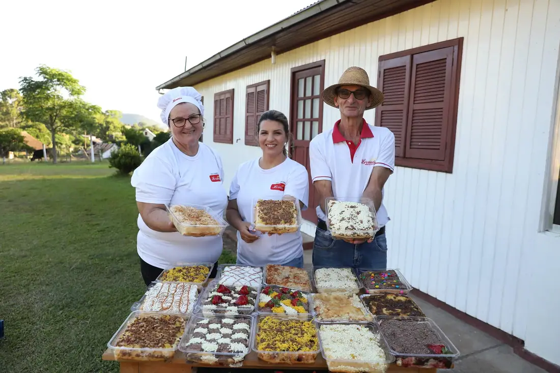 Equipe Hermes com a mesa de tortas em frente à casa, em Linha Rocinha