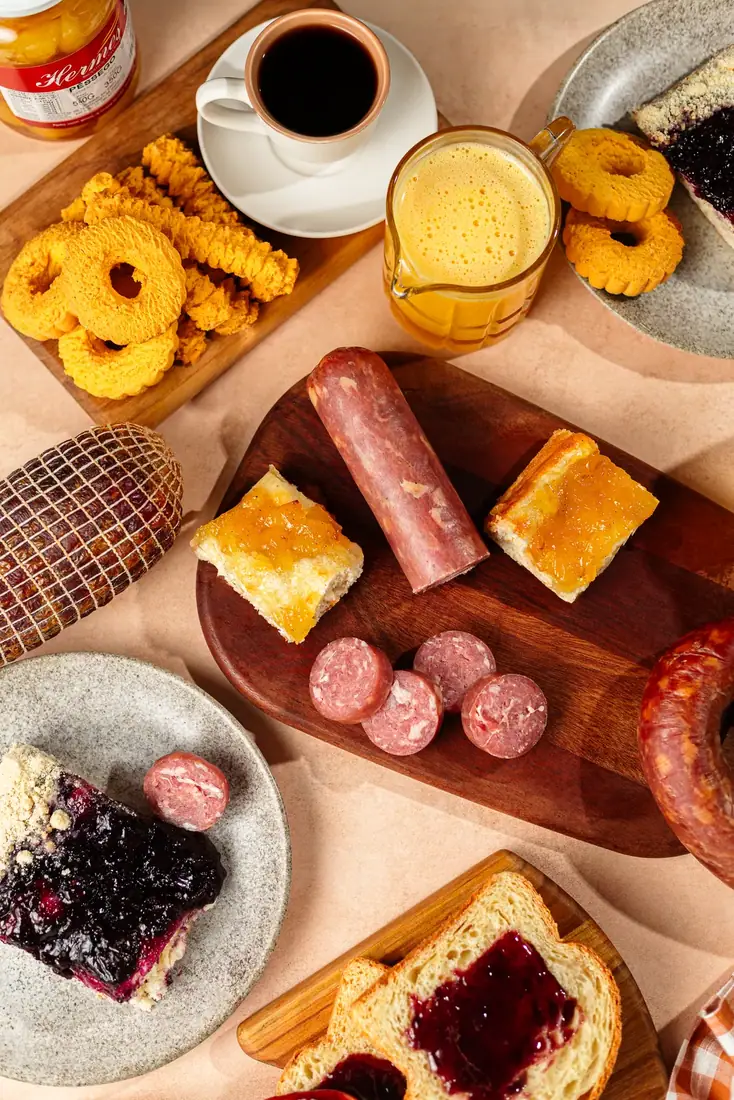 Mesa colonial completa com embutidos, pães, cuca e biscoitos