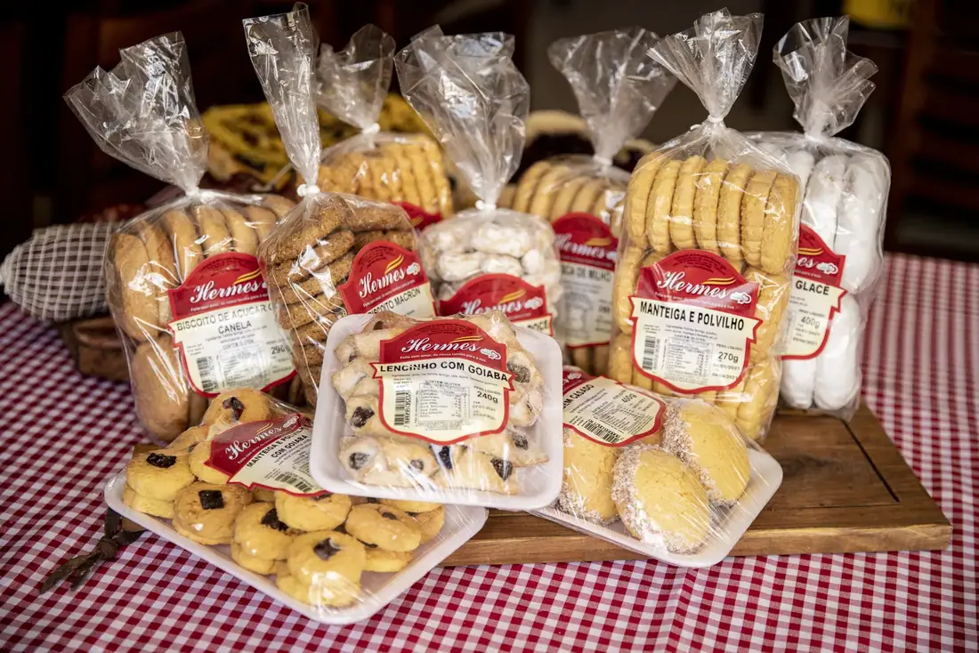 Variedade de biscoitos e roscas Hermes embalados sobre toalha xadrez